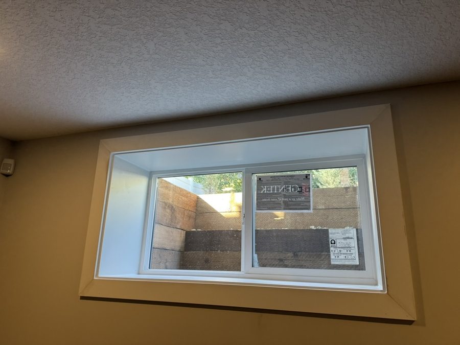 After — finished egress window in basement bedroom with white casement trim, Calgary