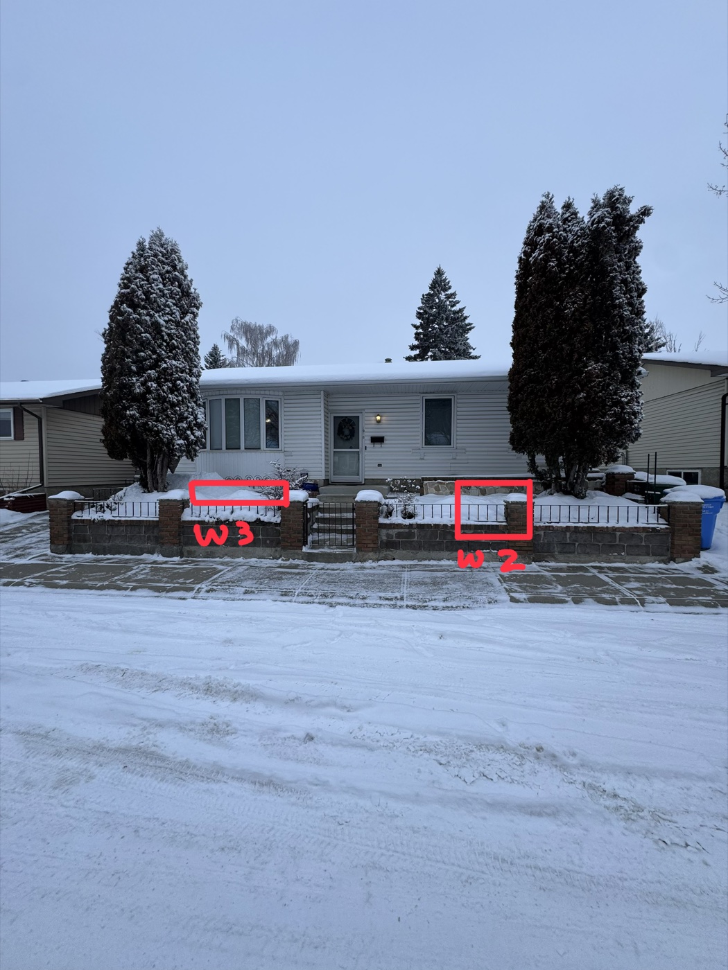 Before — exterior of Calgary home in winter showing existing small windows to be replaced with egress