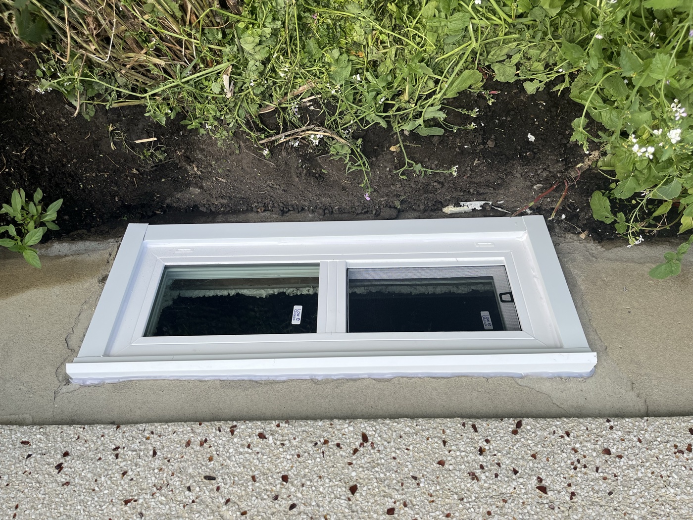 Finished egress window with galvanized well on Calgary home exterior