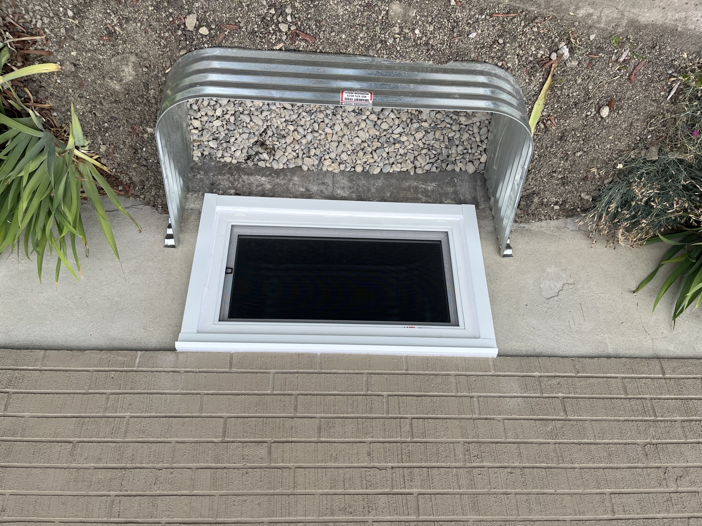 Egress window with galvanized well — finished exterior installation Calgary