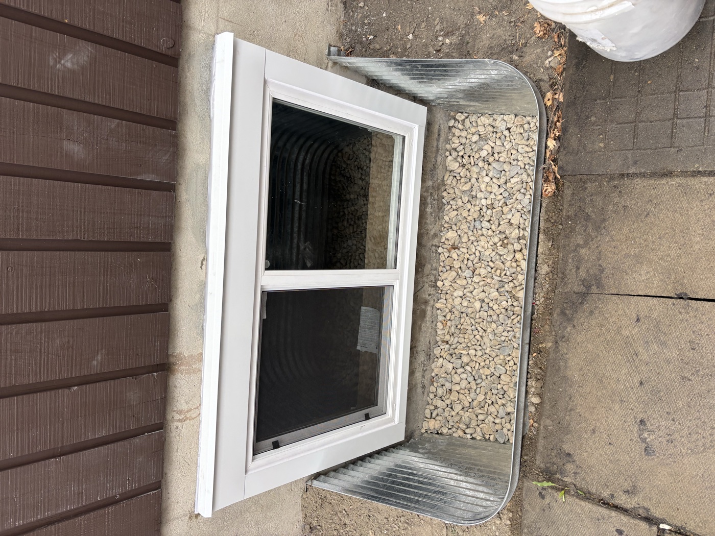 Newly installed egress window with galvanized window well — Calgary home
