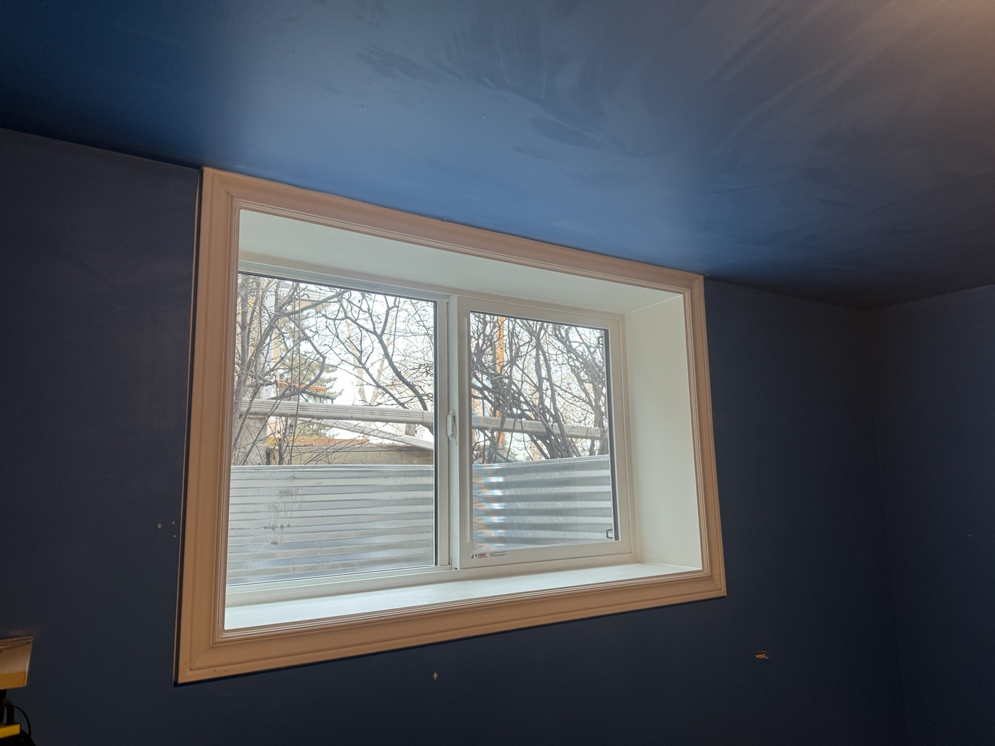Interior finished egress window with white trim — Calgary suite bedroom